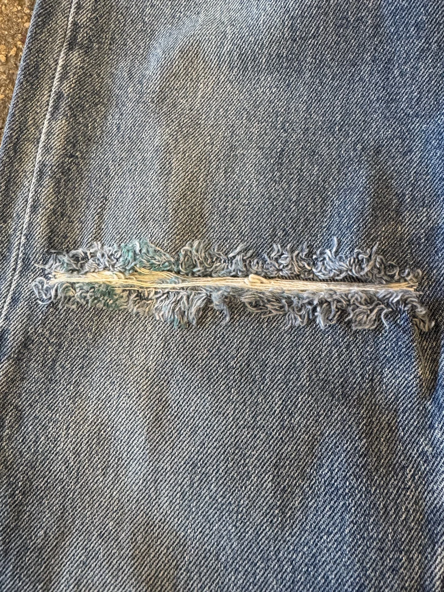 Déchirure dans le denim avec fils apparents